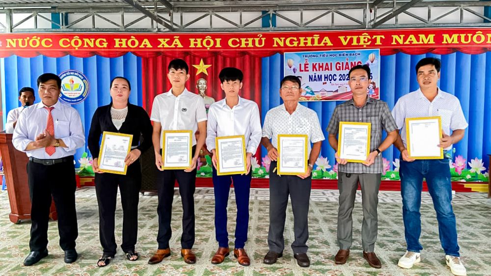 Ông Đinh Chí Công (bìa trái) Hiệu trưởng trường Tiểu học Biển Bạch trao thư cảm ơn cho đại diện các doanh nghiệp, cá nhân ủng hộ cho trường nhân dịp khai giảng năm học mới. 