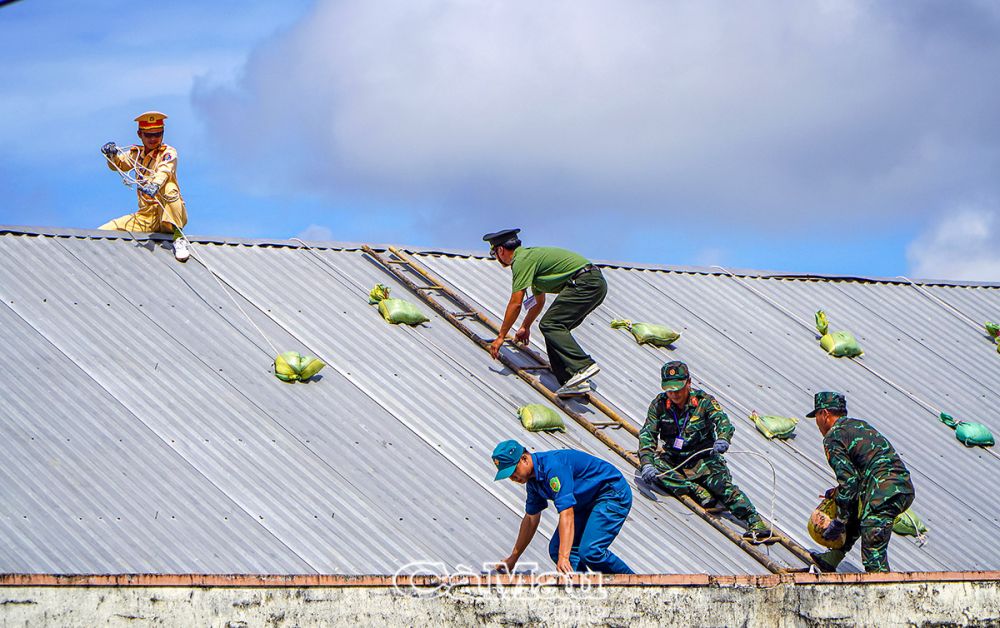 Lực lượng công an và quân sự thực hành chằng, chống công trình nhà ở.