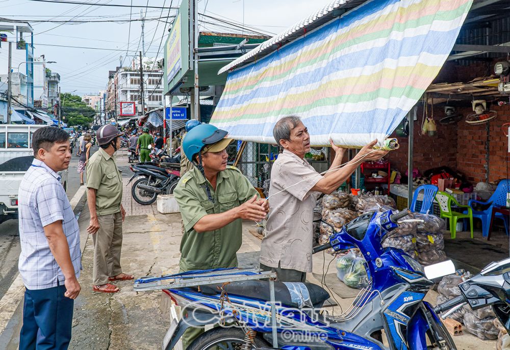 Lực lượng chức năng tháo mái che lấn chiếm vỉa hè tại chợ Phường 7.