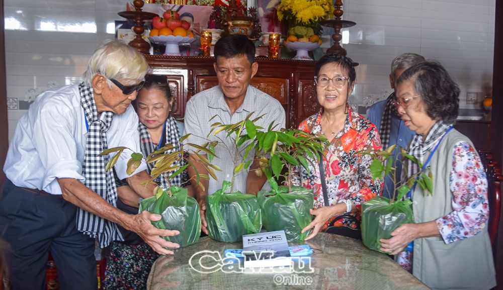 Ông Lê Thanh Hùng (thứ ba từ trái sang), cháu nội, người trực tiếp thờ cúng má Lê Thị Sảnh, thực hiện nghi thức trao cây vú sữa trong vườn nhà má Sảnh cho đoàn (từ phải sang: bà Châu Nhật Sinh và bà Huỳnh Xuân Thảo).