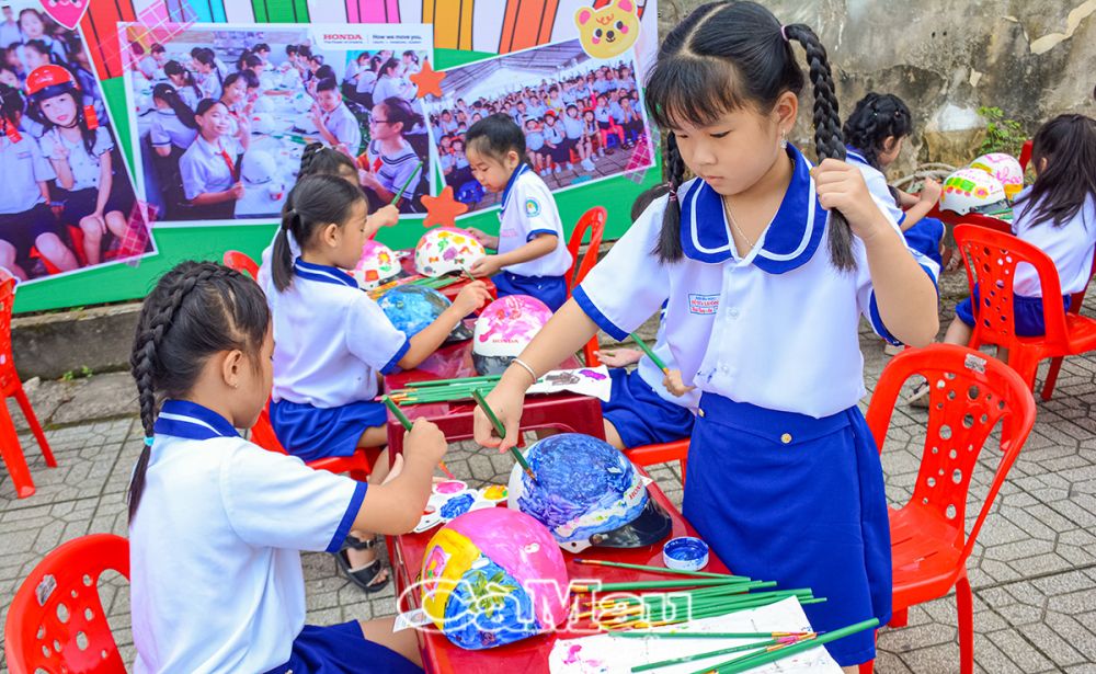 Các em học sinh Trường Tiểu học Đỗ Thừa Luông tham gia hoạt động trang trí nón bảo hiểm có thưởng.