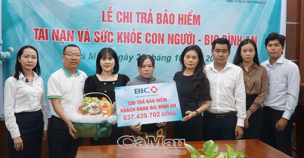 Bà Trương Thị Kim Ngân, Phó giám đốc Ngân hàng BIDV Đất Mũi (mặc áo đen bên trái) cùng với bà Lương Nhã Khanh, giám đốc công ty bảo hiểm BIBV Miền Tây  mặc áo đen trái) trao bản tượng trưng cho gia đình anh Trương Minh Triều.