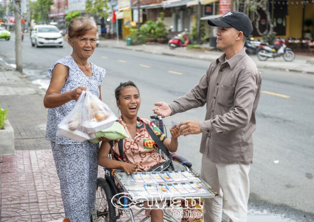 Anh Trần Quốc Toản, chủ vựa gạo ở xã Lý Văn Lâm, TP Cà Mau, một thành viên năng nổ của nhóm, ân cần trao tận tay phần cơm cho mẹ con người bán vé số dạo.