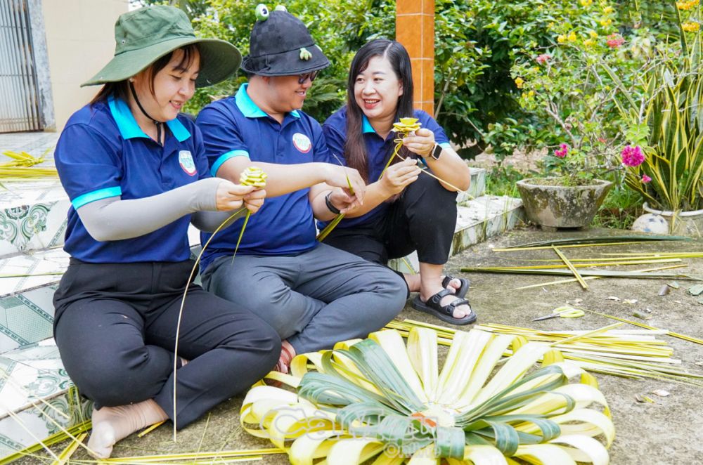 Các bạn trẻ học kỹ thuật đan và kết để trang trí hoa lá cho chiếc cổng cưới thêm xinh.