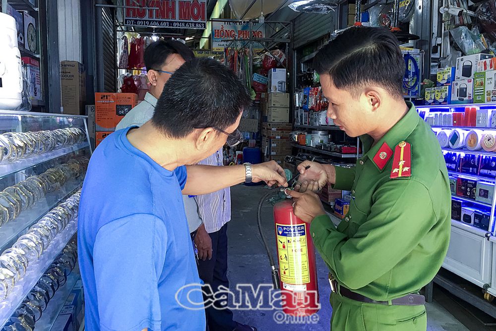 Ðội Cảnh sát quản lý hành chính về trật tự xã hội, Công an huyện Cái Nước, hướng dẫn bà con tiểu thương chợ trung tâm thị trấn Cái Nước kiểm tra, bảo quản và vận hành bình chữa cháy xách tay khi có tình huống.