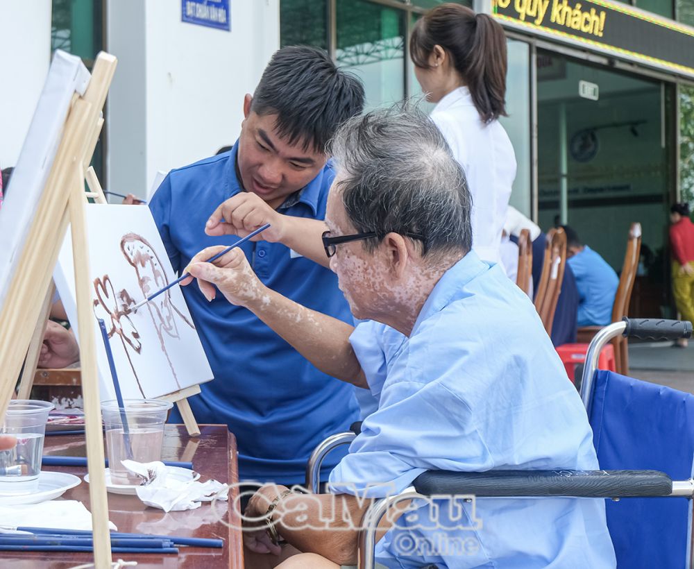 Người bệnh được kỹ thuật viên hướng dẫn thực hiện bức tranh của mình.