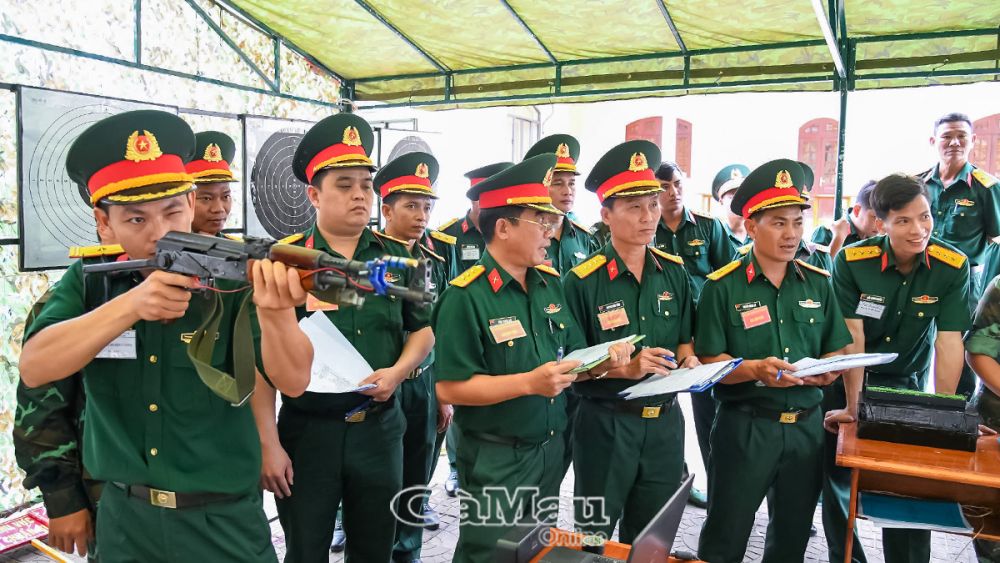 Thiếu tá Mai Vũ Thái (đứng bên trái), Trợ lý Trinh sát Ban CHQS huyện U Minh thực hành bắn súng mô phỏng trong nhà. 