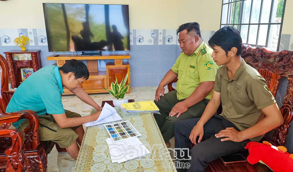 Ông Trần Xây Dựng (bên trái) ký cam kết thực hiện các quy định trong gây nuôi động vật hoang dã (trăn đất).