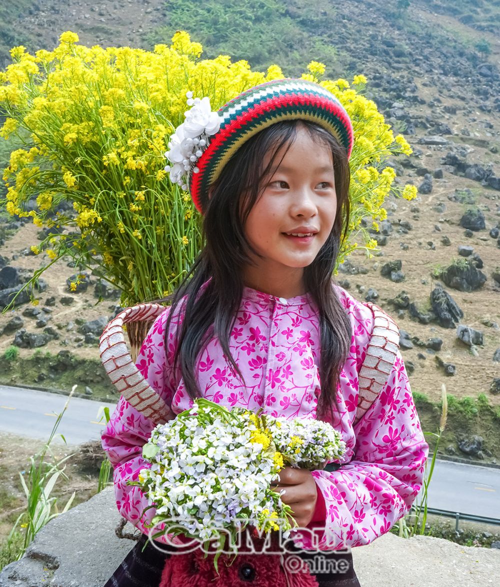 Em bé dân tộc H'Mông tại đèo Mã Pì Lèng với nụ cười tươi sáng và trang phục truyền thống.