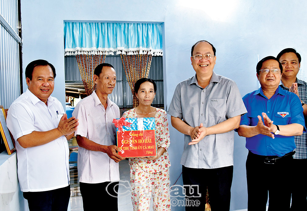 Ðồng chí Nguyễn Hồ Hải, Bí thư Tỉnh uỷ (thứ tư từ trái sang) tặng quà cho hộ dân được hỗ trợ nhà tại phường Hoà Thành. (Ảnh: MỘNG THƯỜNG)