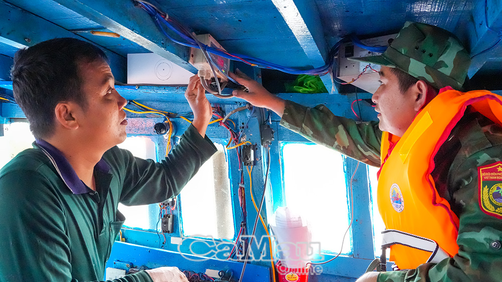 Cán bộ Ðồn Biên phòng Rạch Gốc kiểm tra thiết bị giám sát hành trình tàu cá trên phương tiện của anh Võ Minh Ðạt.