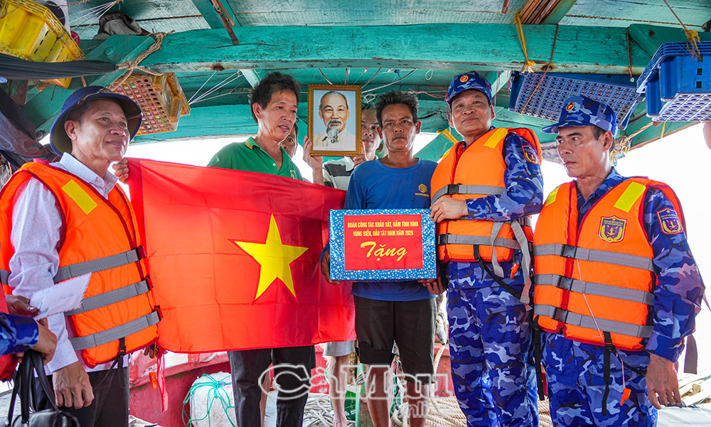 Thiếu tướng Trần Văn Xuân, Phó Chính uỷ Cảnh sát biển Việt Nam (thứ hai từ phải sang) và đồng chí Trần Hữu Phước, Trưởng ban Nội chính Tỉnh uỷ Cà Mau (bìa trái) trao tặng cờ Tổ quốc, ảnh Bác Hồ và quà cho ngư dân đang khai thác hải sản trên vùng biển Tây Nam trong chuyến khảo sát, nắm tình hình biển, đảo Tây Nam năm 2026.